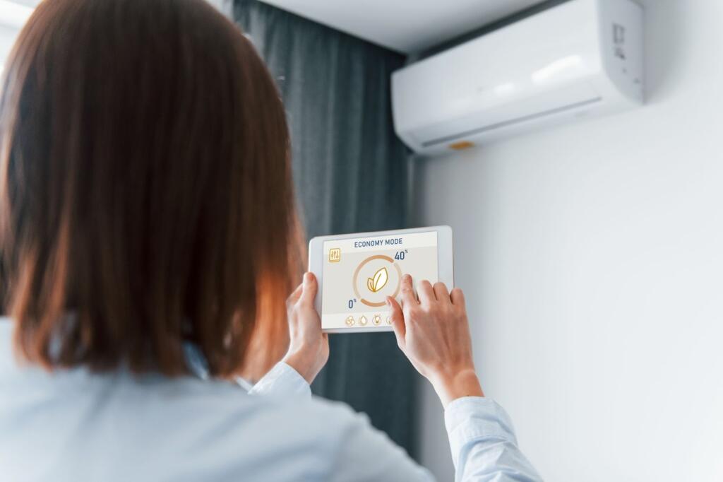 A woman is controlling an air conditioning unit with her tablet. 