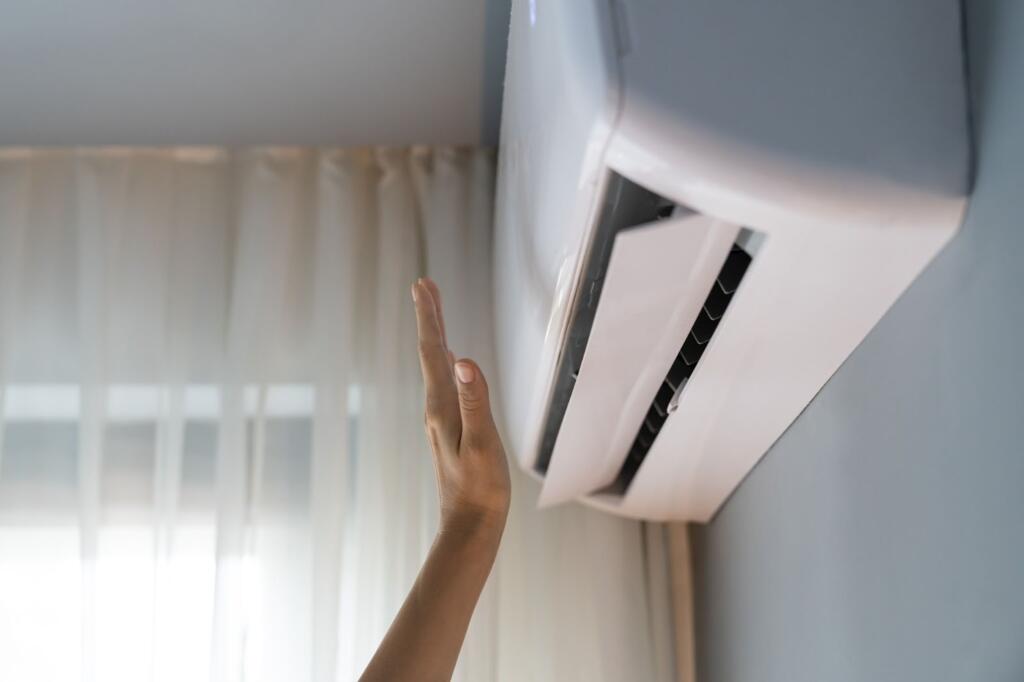 Apartment owner checking the wall-mounted air conditioner’s airflow with his hand