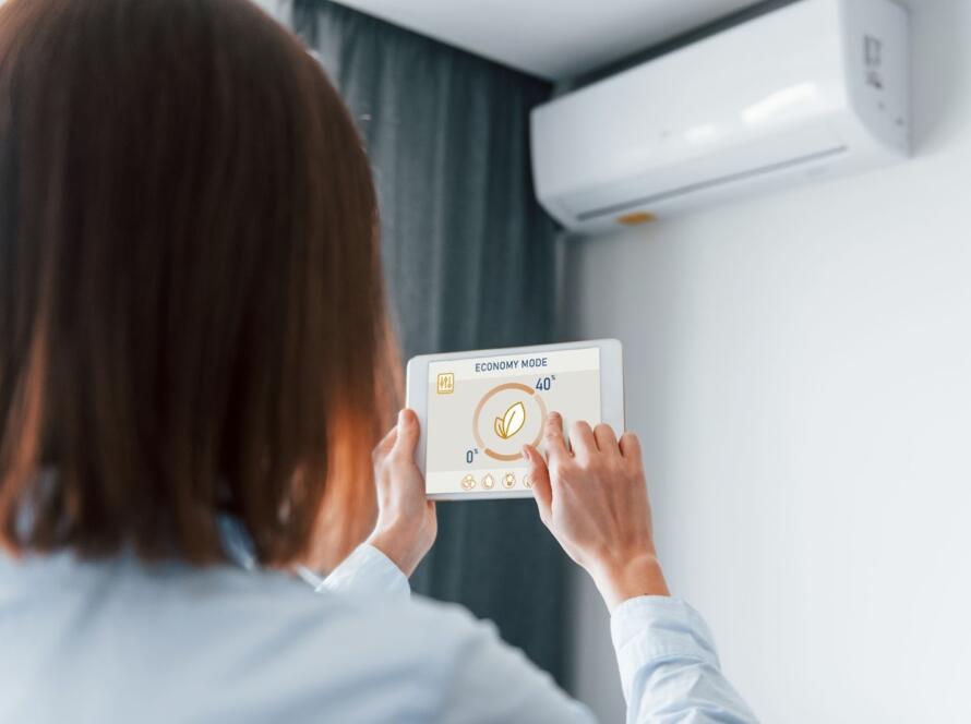 A woman is controlling an air conditioning unit with her tablet. 