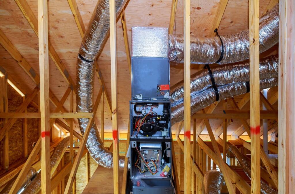 Installation of an energy recovery ventilator (ERV) during home construction, with roof vent pipes and connected duct system visible