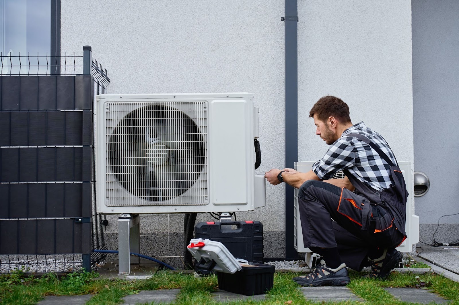 Professional HVAC technician inspecting an outdoor heat pump system
