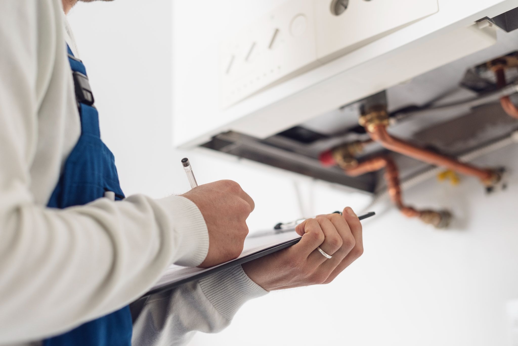 Close-up of a boiler maintenance crew recording inspection details on a clipboard